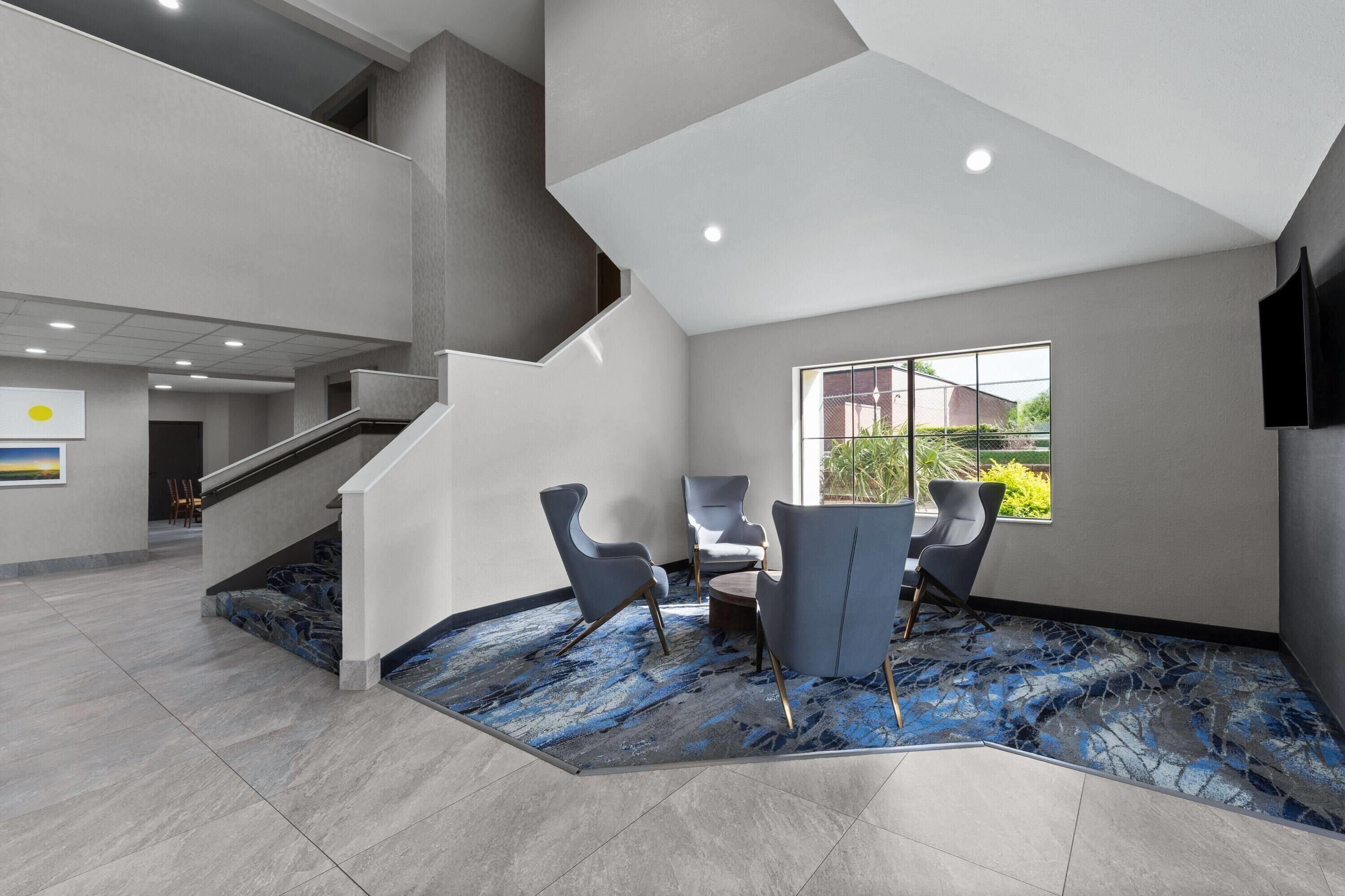 A modern interior with a staircase, seating area, and a large window.