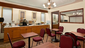 A dining area with wooden tables and red chairs, a kitchen counter with various appliances, and a chandelier.