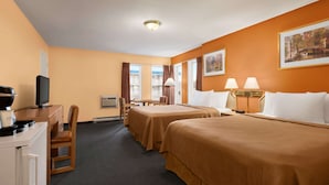 A hotel room with two beds, a desk with a computer, a chair, a television, and a window with curtains.
