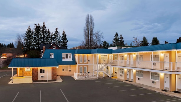 A motel with multiple floors, a parking lot, and a small building with a blue roof.