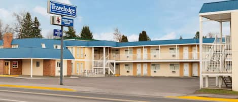 Un motel Travelodge con techo azul, varias habitaciones y un letrero que indica piscina climatizada y sauna.