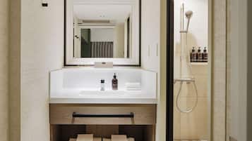 Un baño moderno con un espejo grande, un lavamanos y una ducha.