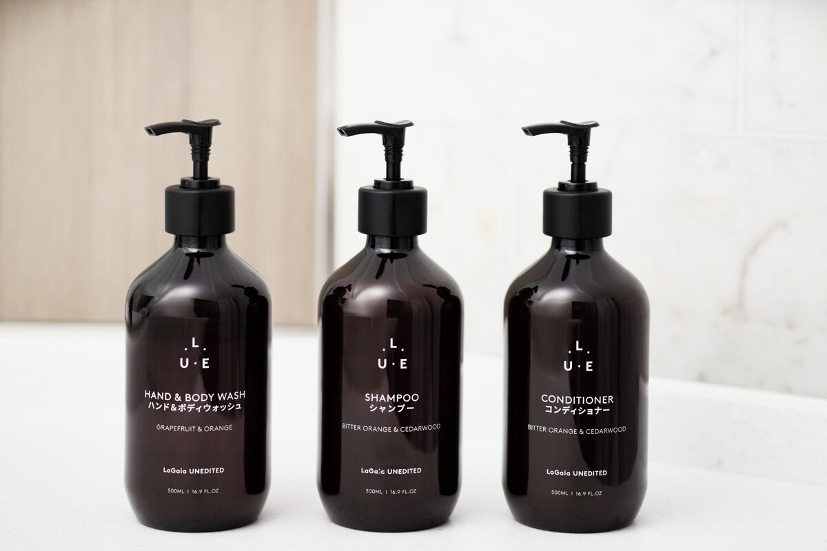 Three bottles of L.U.E. hand and body wash, shampoo, and conditioner on a white surface.