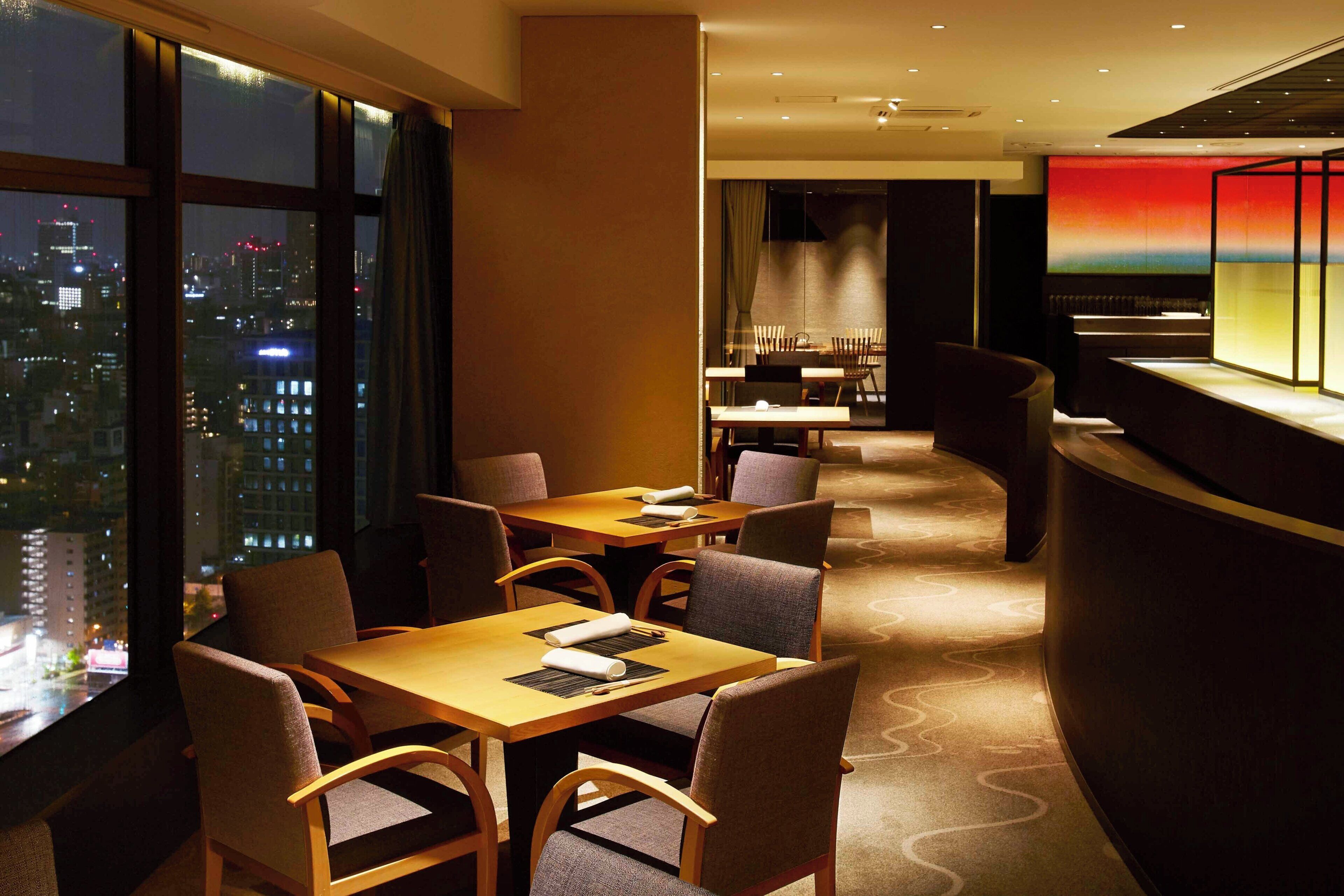 A hotel lobby with a reception desk, seating area, and large windows offering a city view.