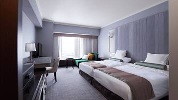 Habitación de hotel con dos camas, un escritorio, una silla y una ventana con cortinas.