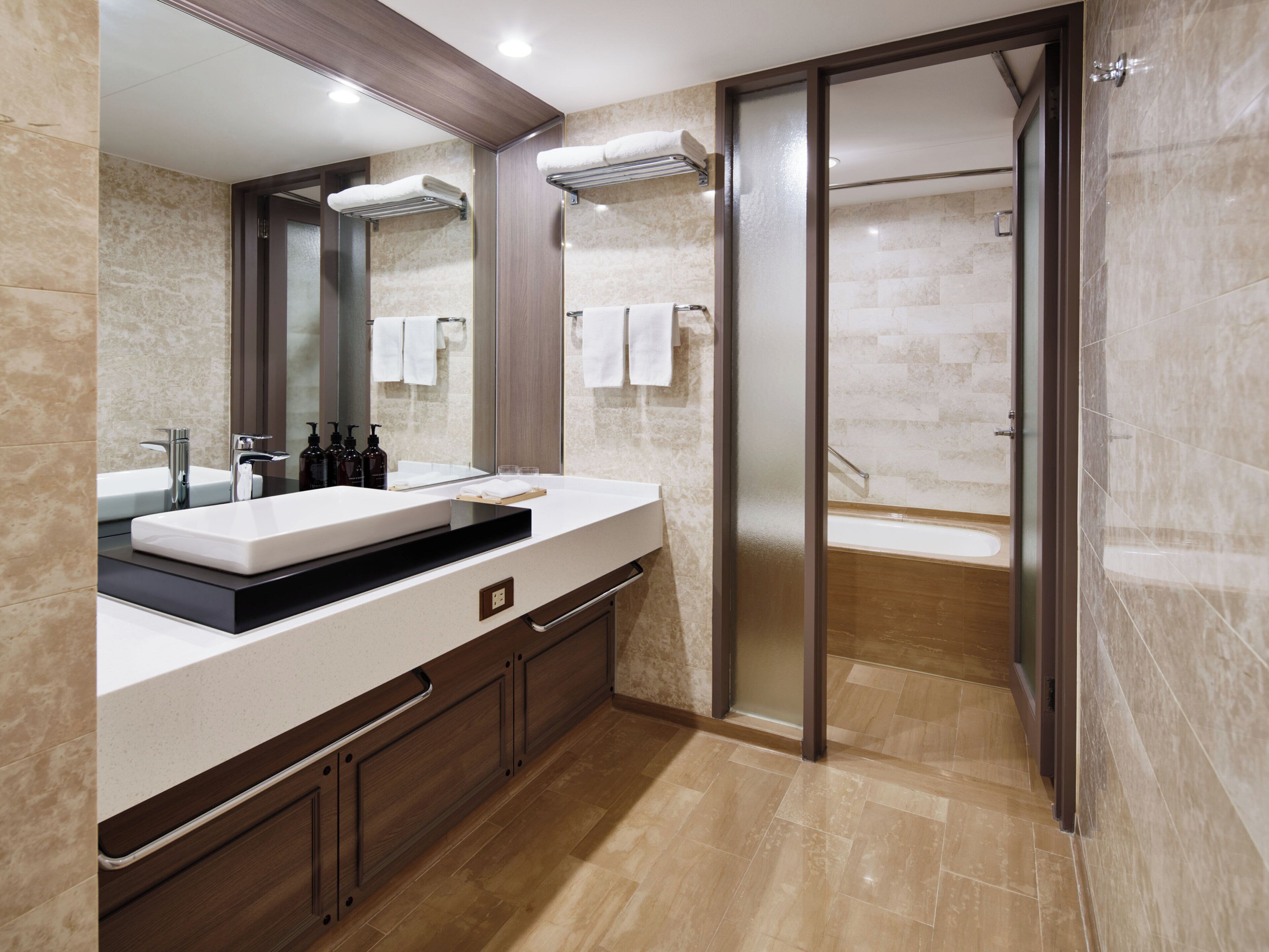 Un baño moderno con un espejo grande, dos lavamanos, una bañera y una ducha a ras de suelo.