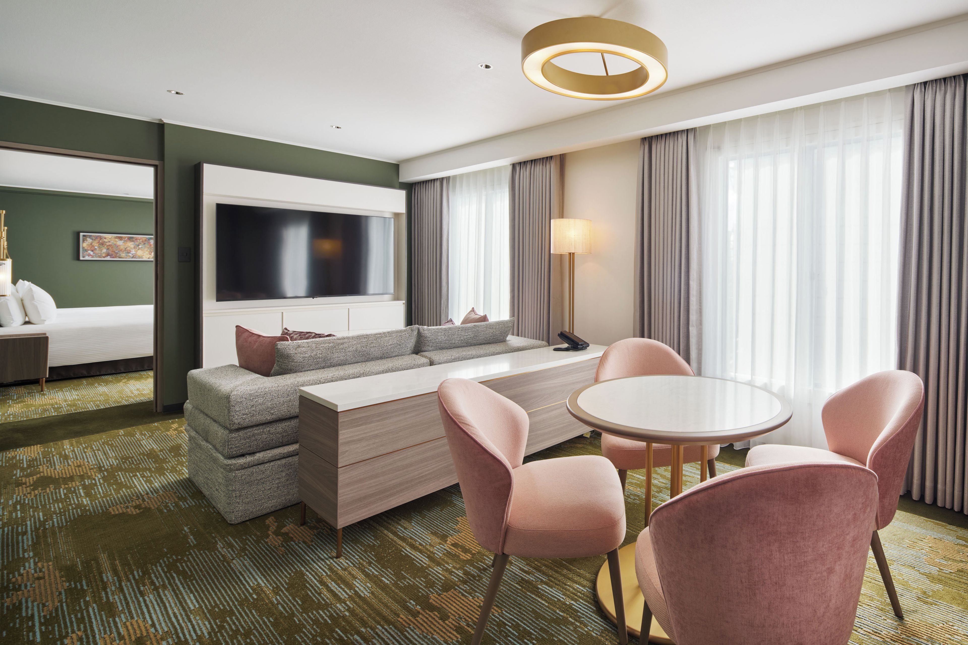 A hotel room with a sofa, a TV, a dining table, and chairs.