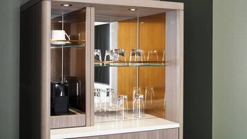 A cabinet with glass shelves displaying clear glassware and a white cup.