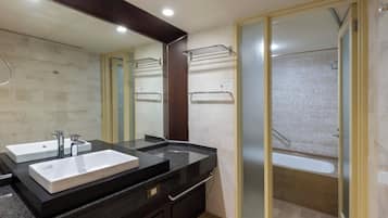 A modern bathroom with two sinks, a large mirror, and a walk-in shower.