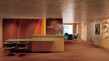 A reception area with a wooden reception desk, two chairs, a vase with flowers, and a bookshelf.