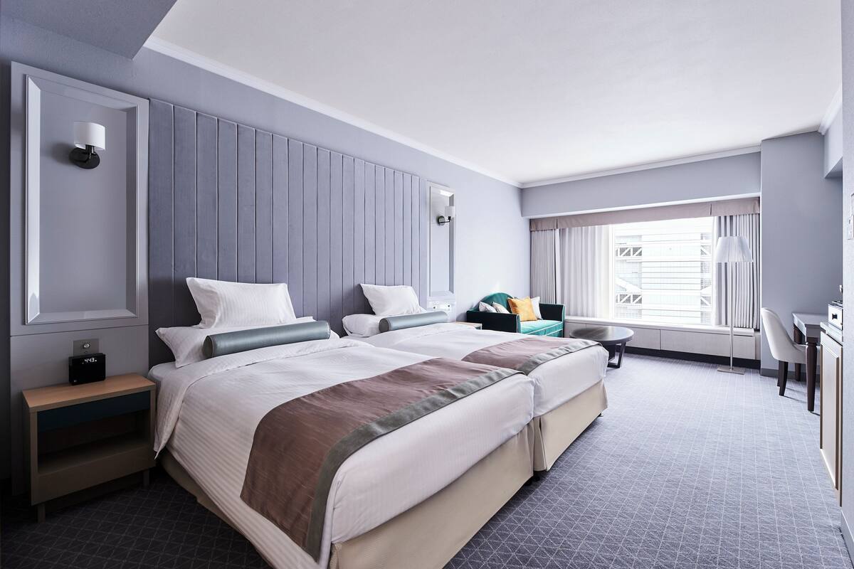 Une chambre d’hôtel moderne avec un grand lit, un bureau, une chaise et une fenêtre avec des rideaux.