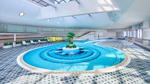 An indoor swimming pool with a central island, surrounded by lounge chairs and a tiled floor. - RIHGA Royal Hotel Osaka, Vignette Collection by IHG (Osaka)