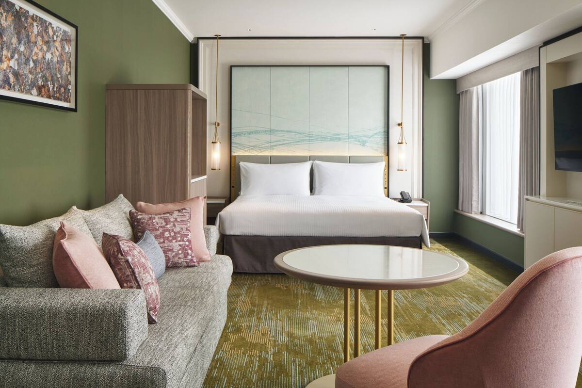 Une chambre d’hôtel avec un lit, un canapé, une table ronde et un téléviseur.