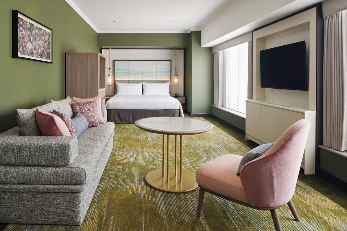 Une chambre d’hôtel avec un lit, un canapé, une table ronde et un téléviseur.