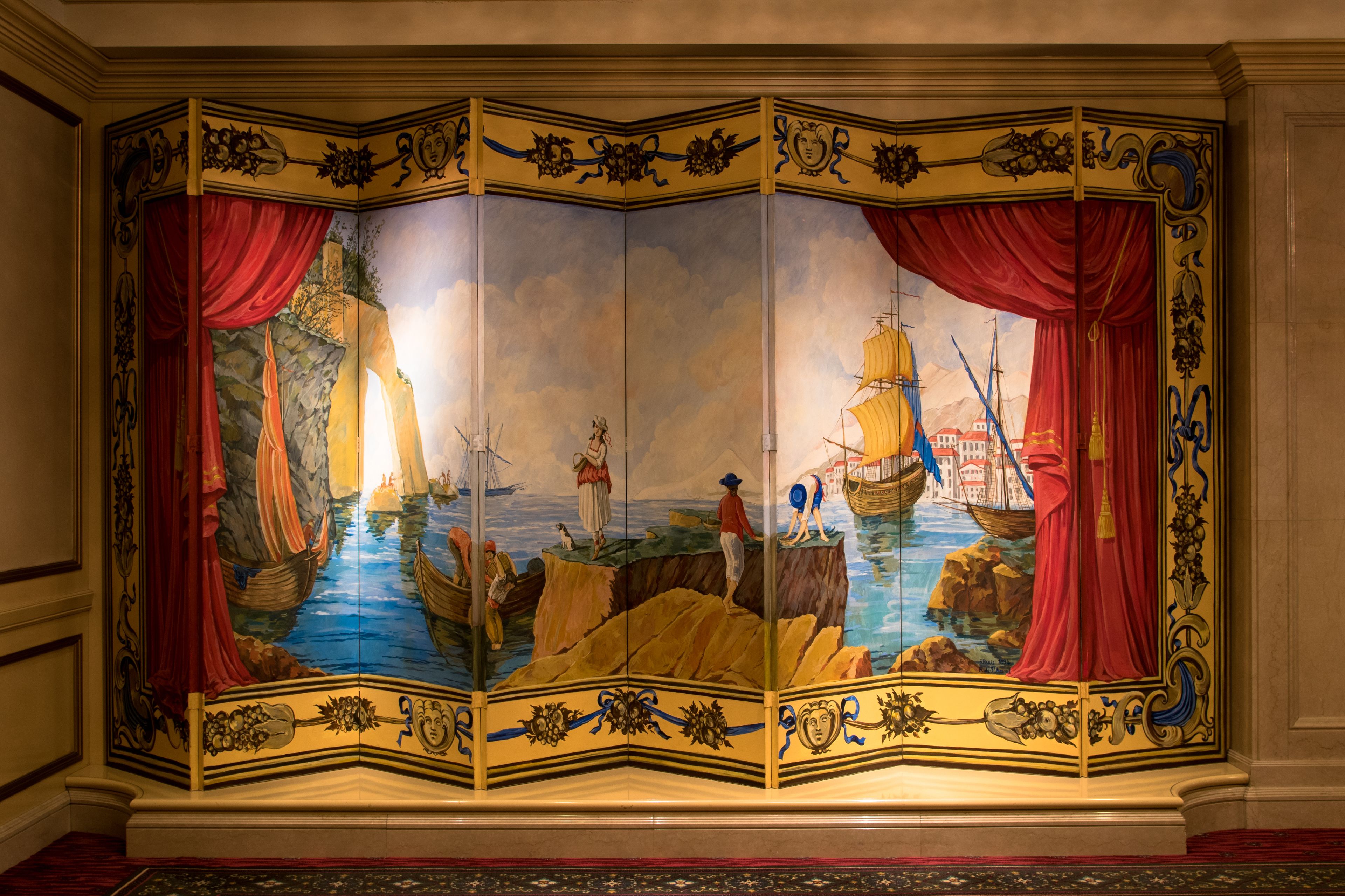 A room with a large, ornate, multi-panel screen depicting a maritime scene.