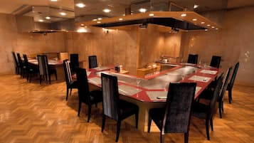 Een vergaderruimte met een lange tafel, meerdere stoelen en een modern plafond.