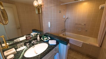 A bathroom with a sink, mirror, vanity, towel rack, and a bathtub.