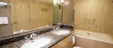Un baño con dos lavamanos, un espejo grande, una bañera y un inodoro.