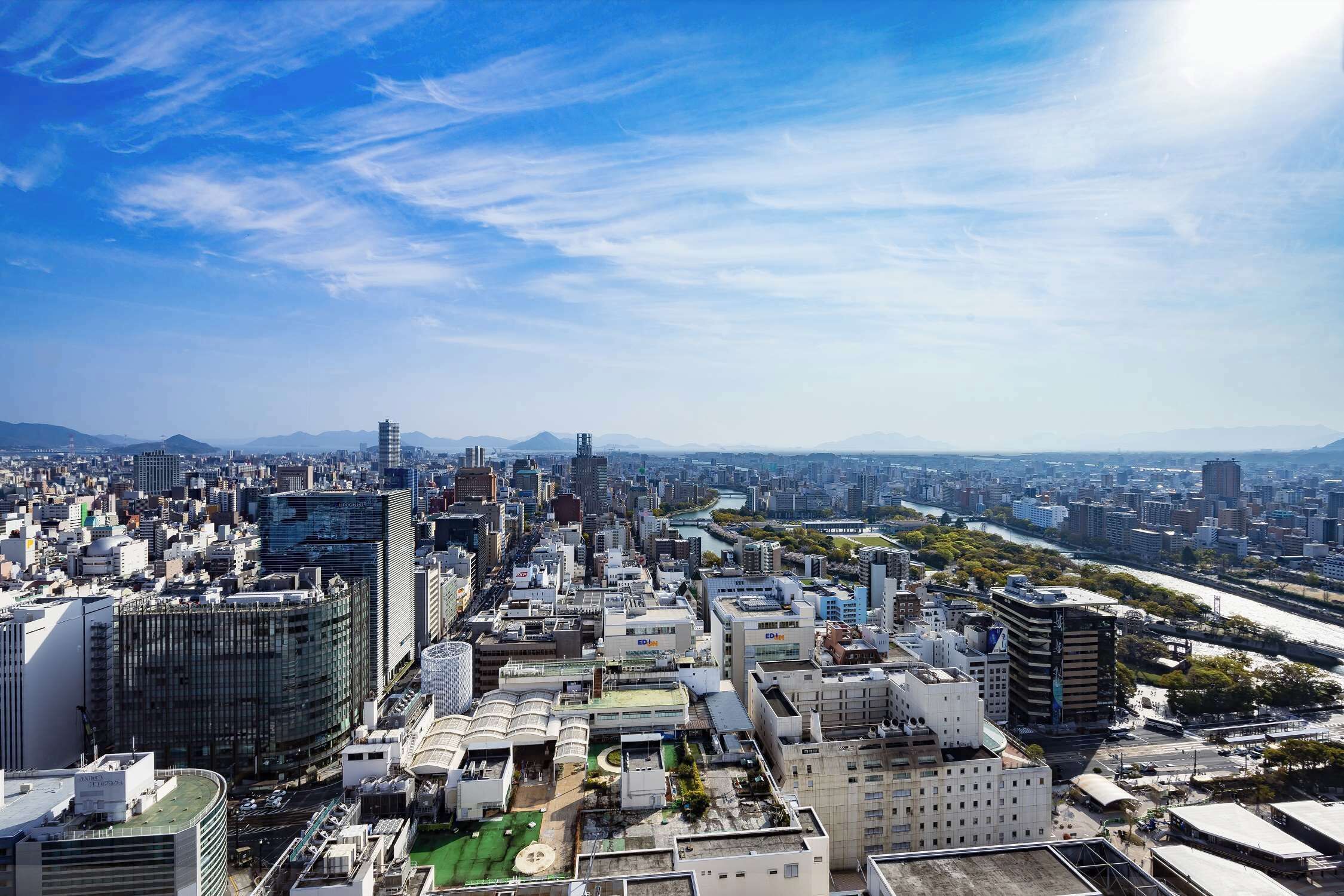 A cityscape with high-rise buildings, a river, and a clear sky.