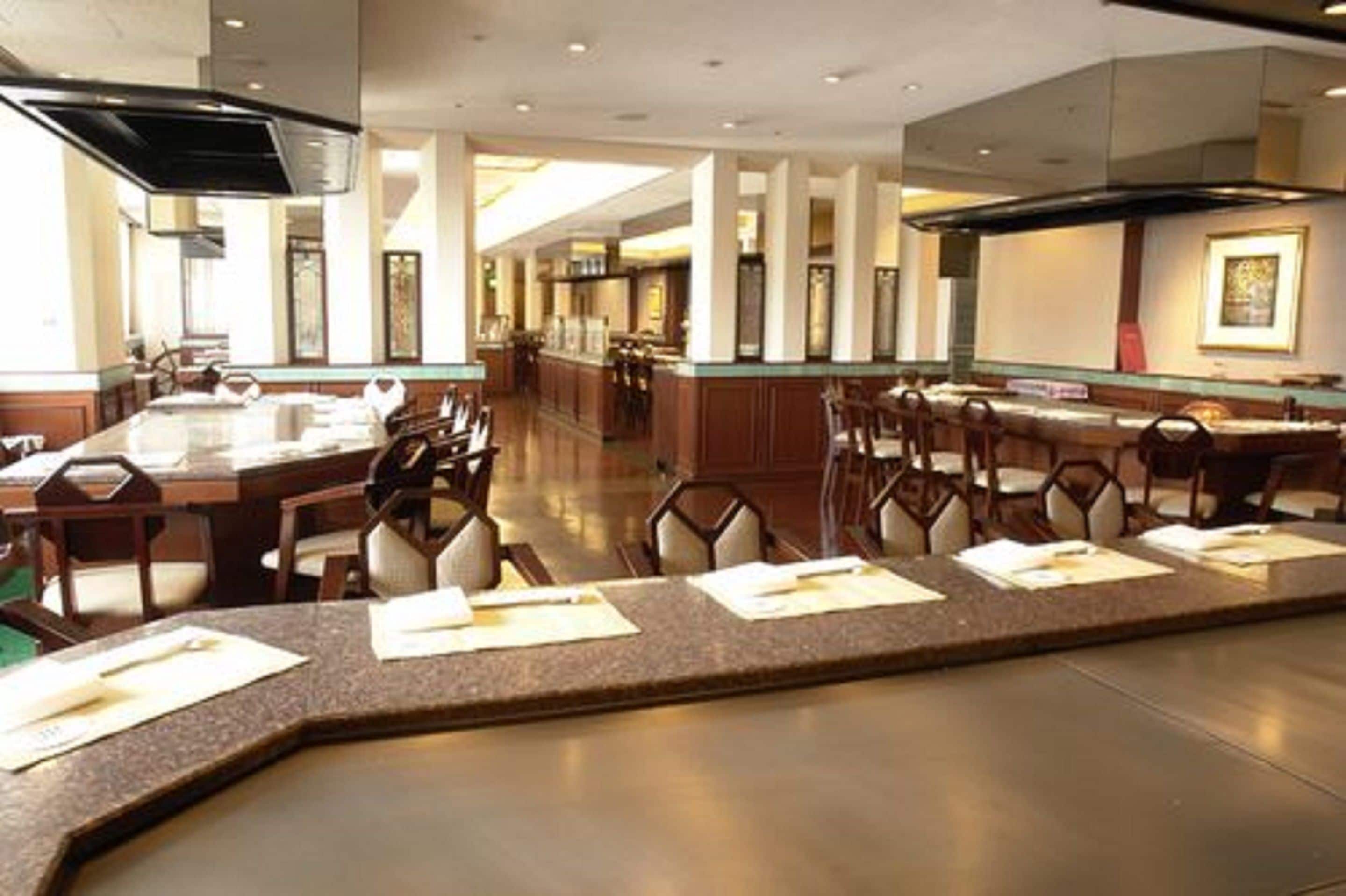 Un amplio comedor de hotel con una barra larga, varias mesas y sillas.