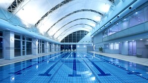 A large indoor swimming pool with a high ceiling and modern architecture. - RIHGA Royal Hotel Hiroshima (Hiroshima)