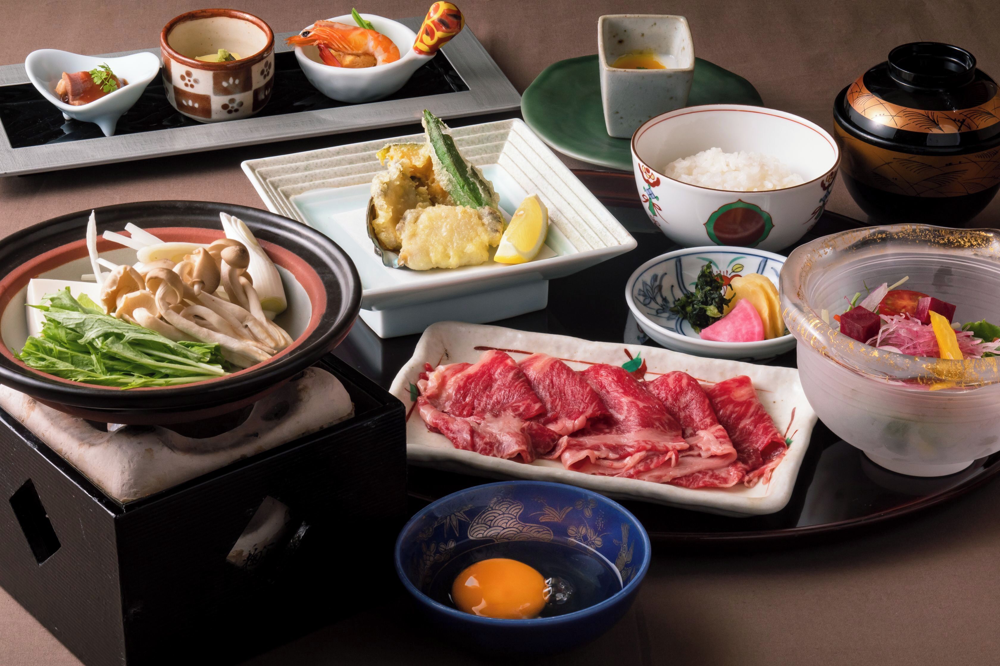 A traditional Japanese meal setup with various dishes, including sashimi, rice, and vegetables.
