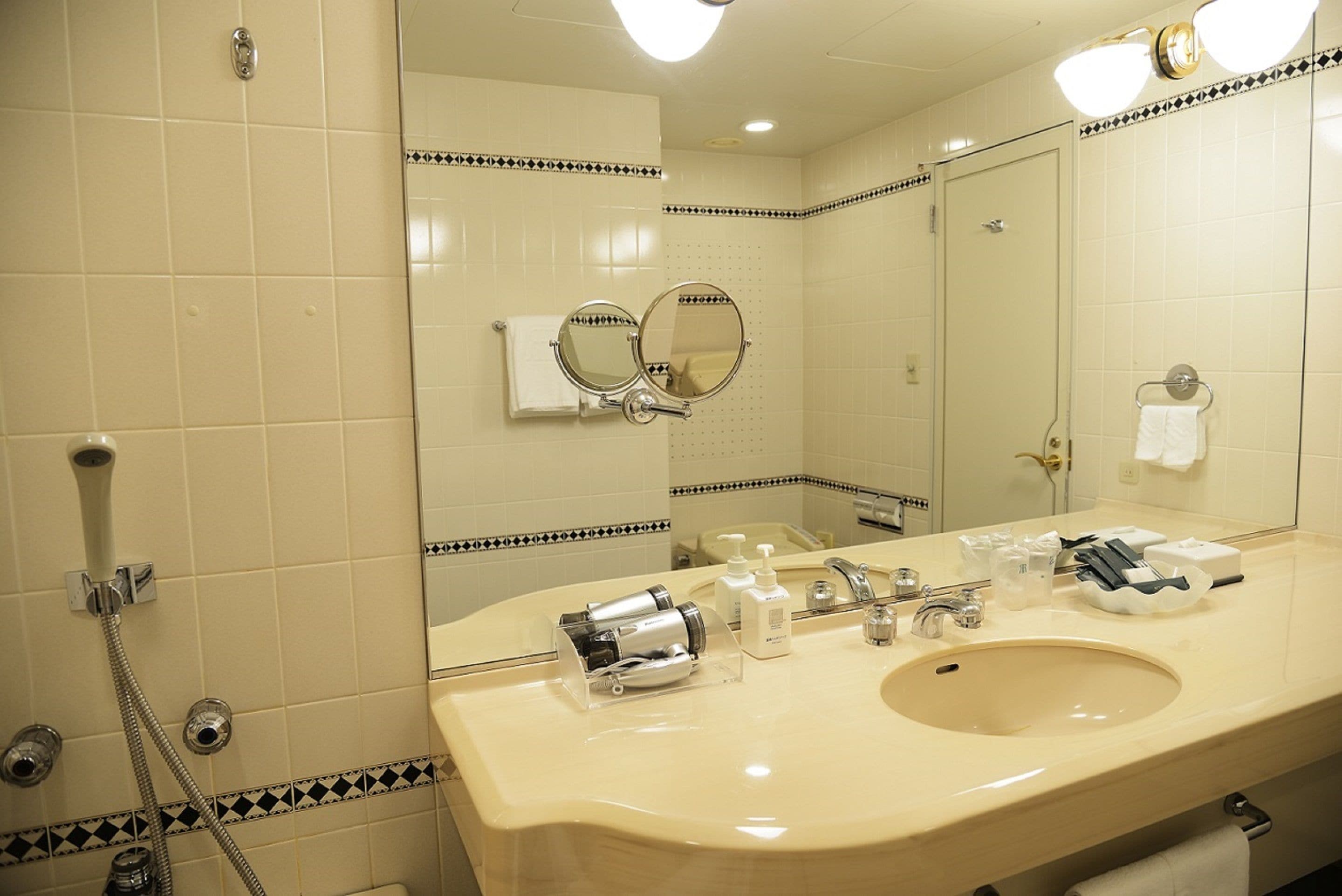 A bathroom with a large mirror, a sink, and a shower.