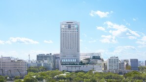 Korkea, moderni rakennus, jonka julkisivussa on ruudukkomainen kuvio, ja jonka ympärillä on muita rakennuksia ja viheralueita.