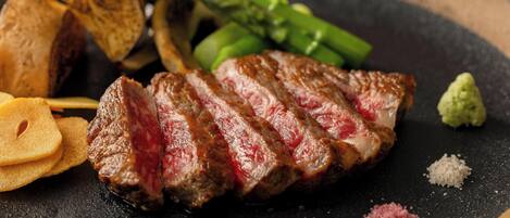 Un plato con bistec en rodajas, espárragos y papas asadas.