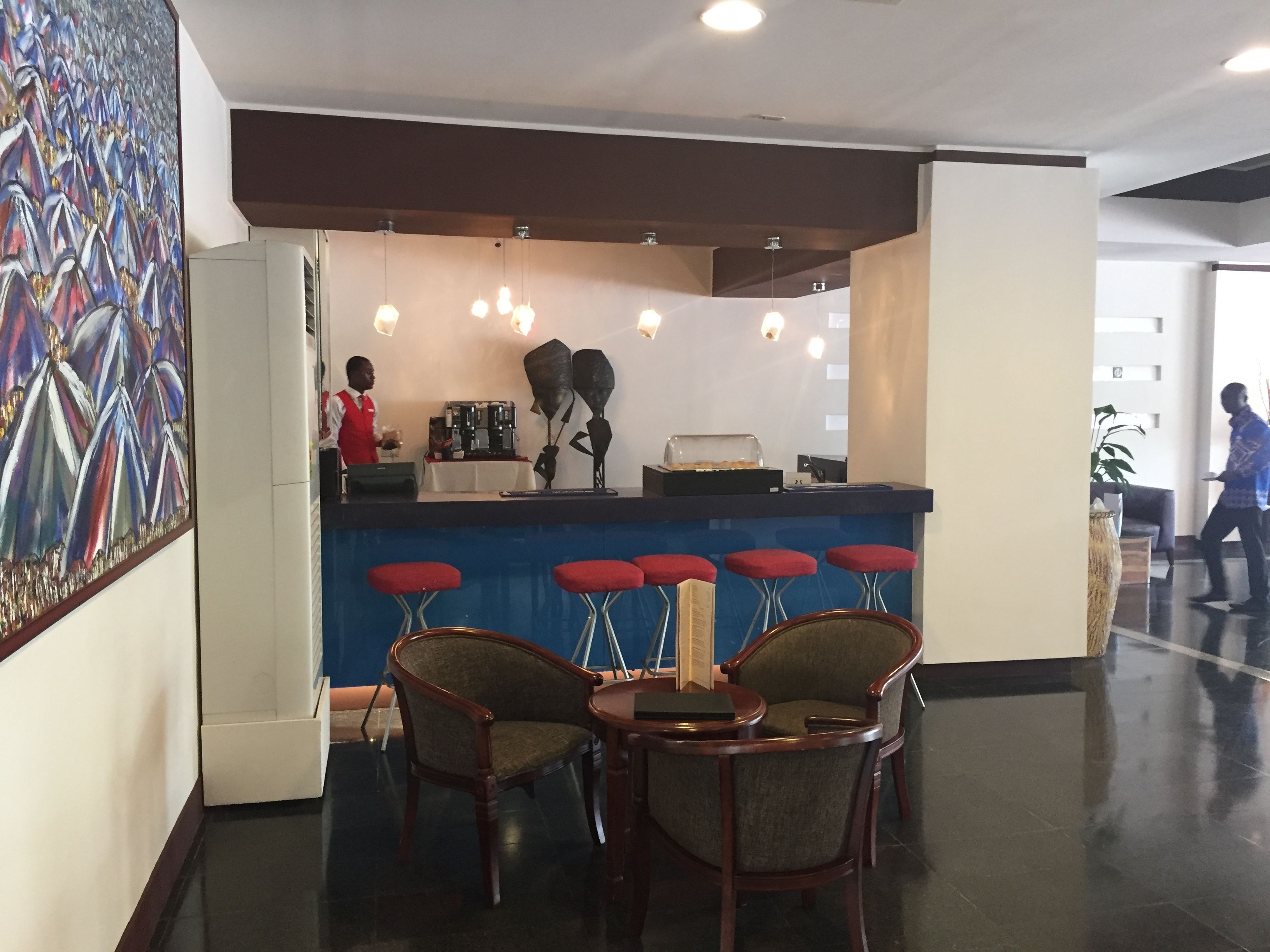 A bar area with a counter, stools, and a coffee machine.