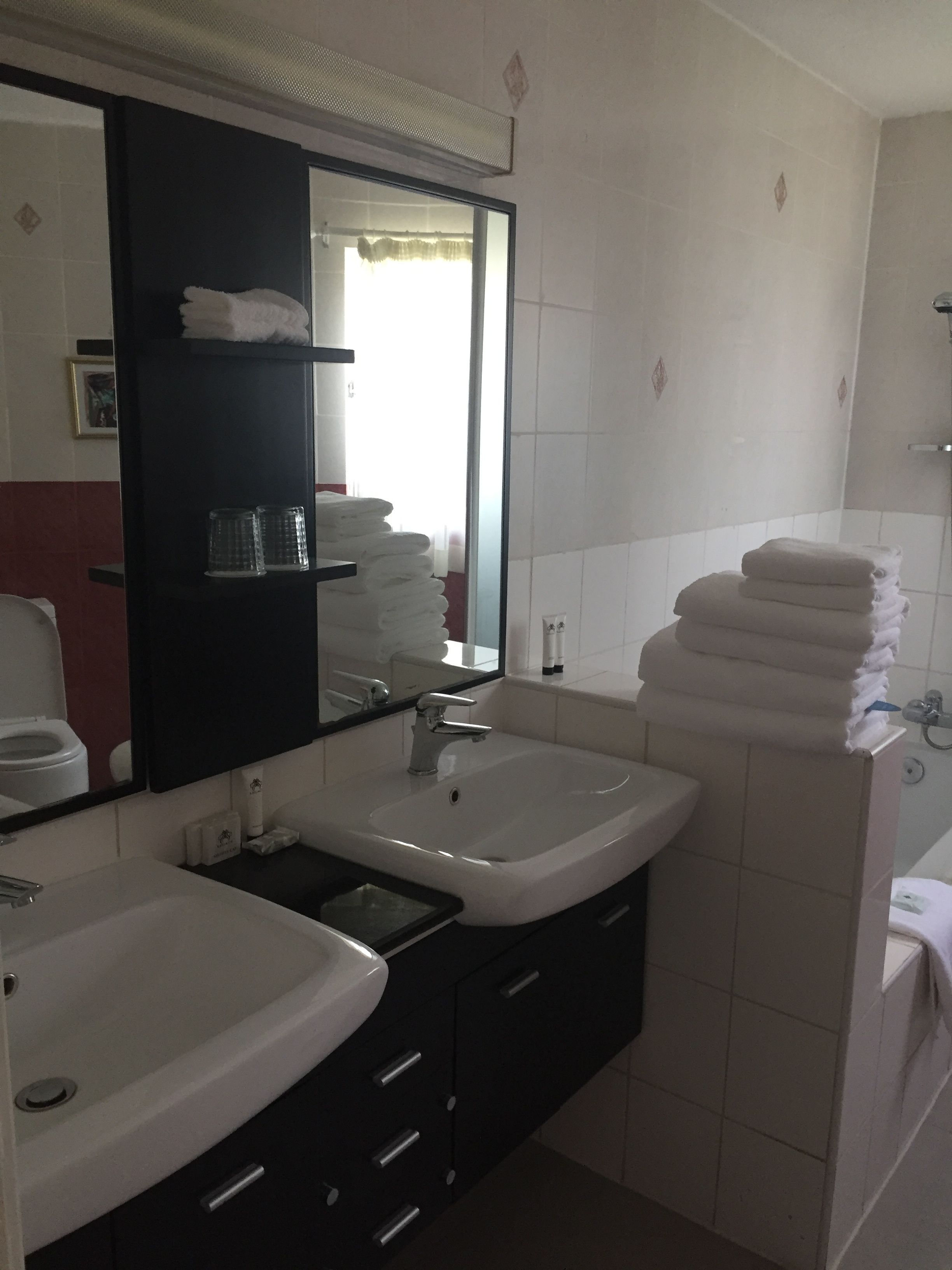 A bathroom with two sinks, a mirror, and a stack of towels.