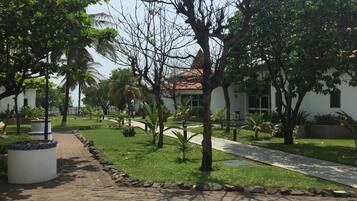 Un sendero conduce a un edificio con un letrero con el número 9, rodeado de follaje y palmeras.