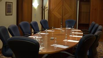 A conference room with a wooden table, blue chairs, and wine glasses set for a meeting.