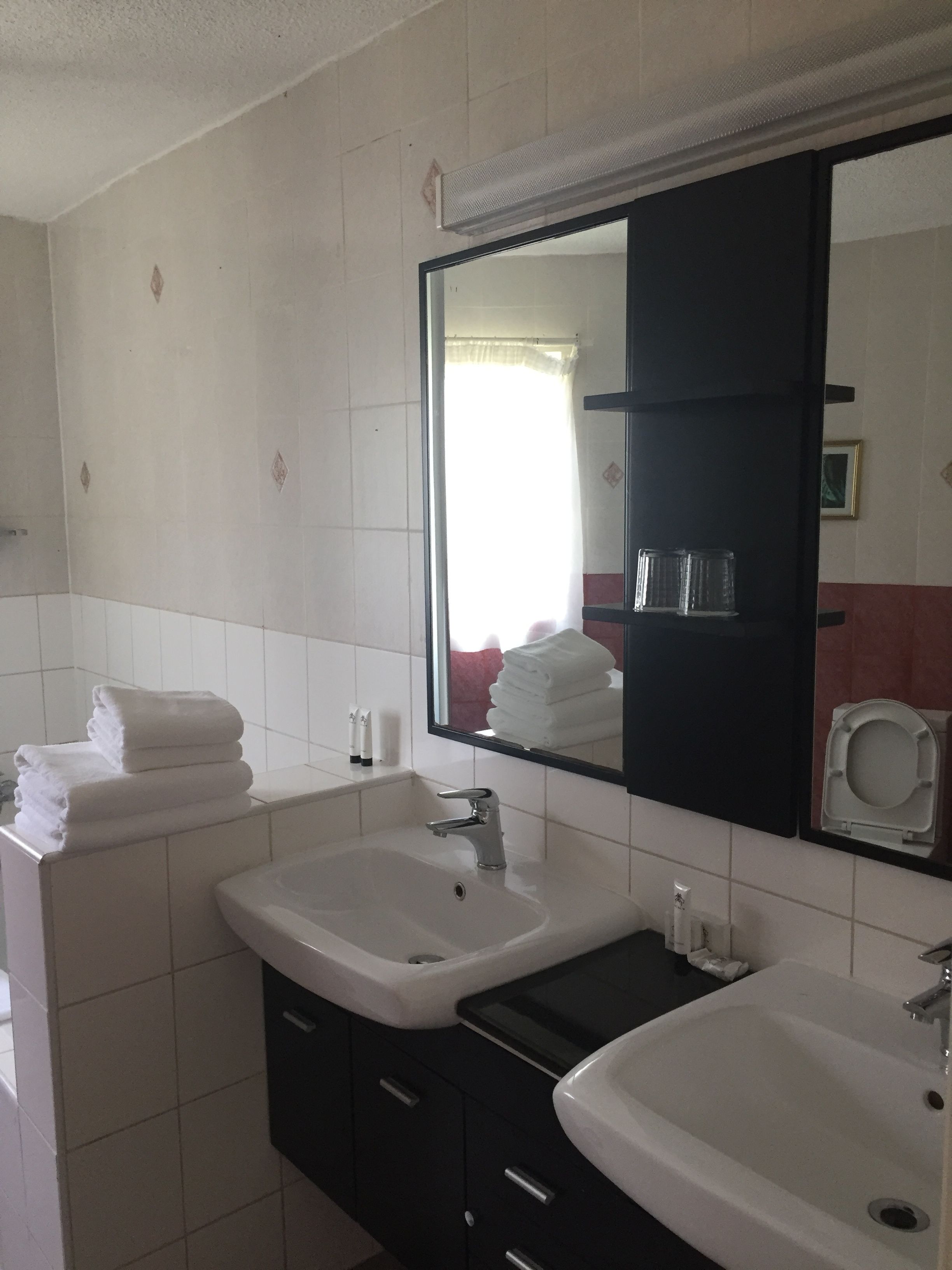 Un baño con dos lavamanos, un espejo y un perchero para toallas.