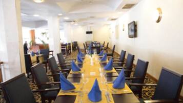 A conference room with a long table set for a meeting, surrounded by chairs.