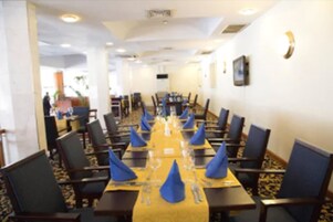 A conference room with a long table set for a meeting, surrounded by chairs.