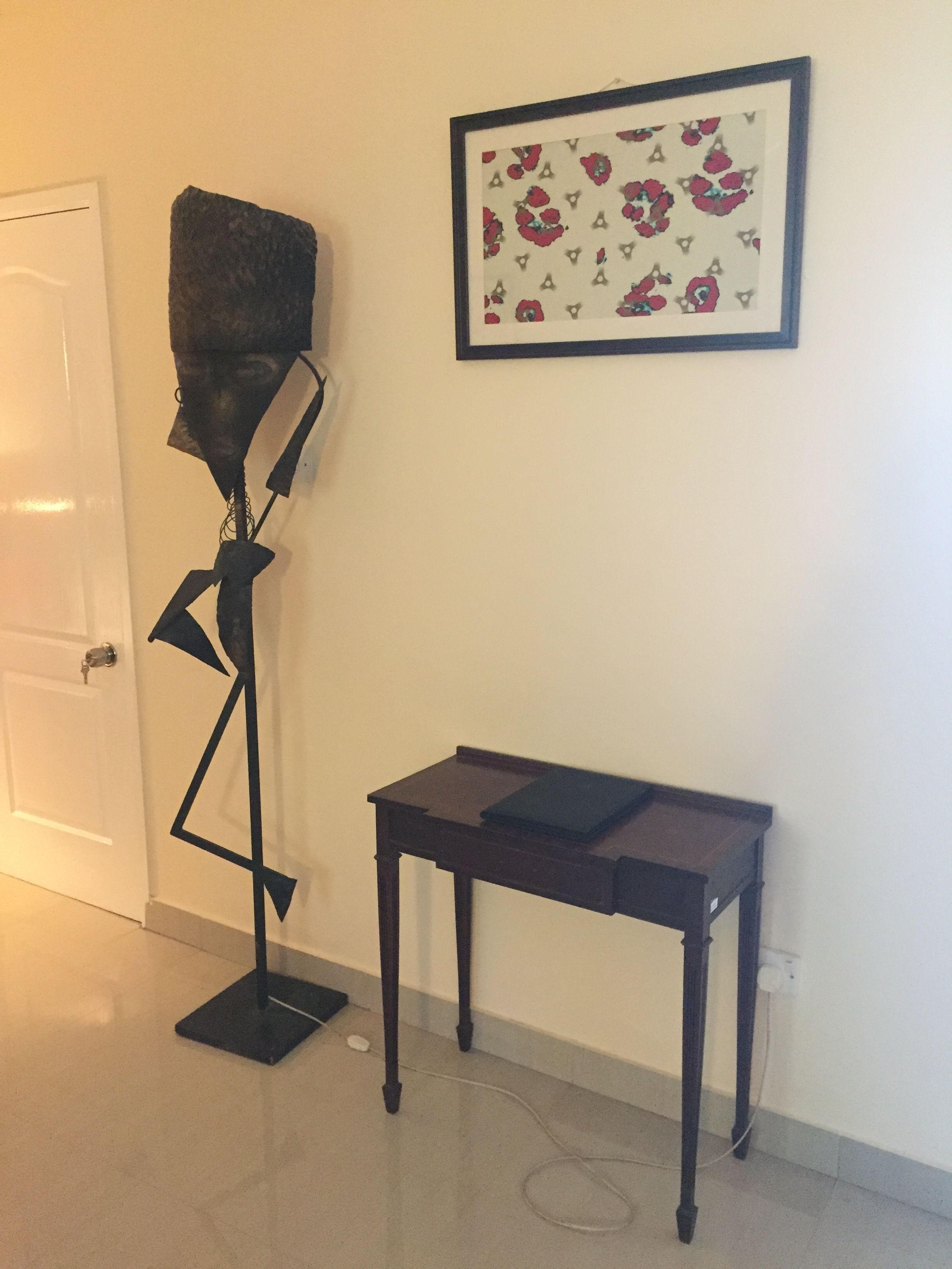 Une pièce avec un lampadaire, une petite table et une œuvre d’art encadrée accrochée au mur.