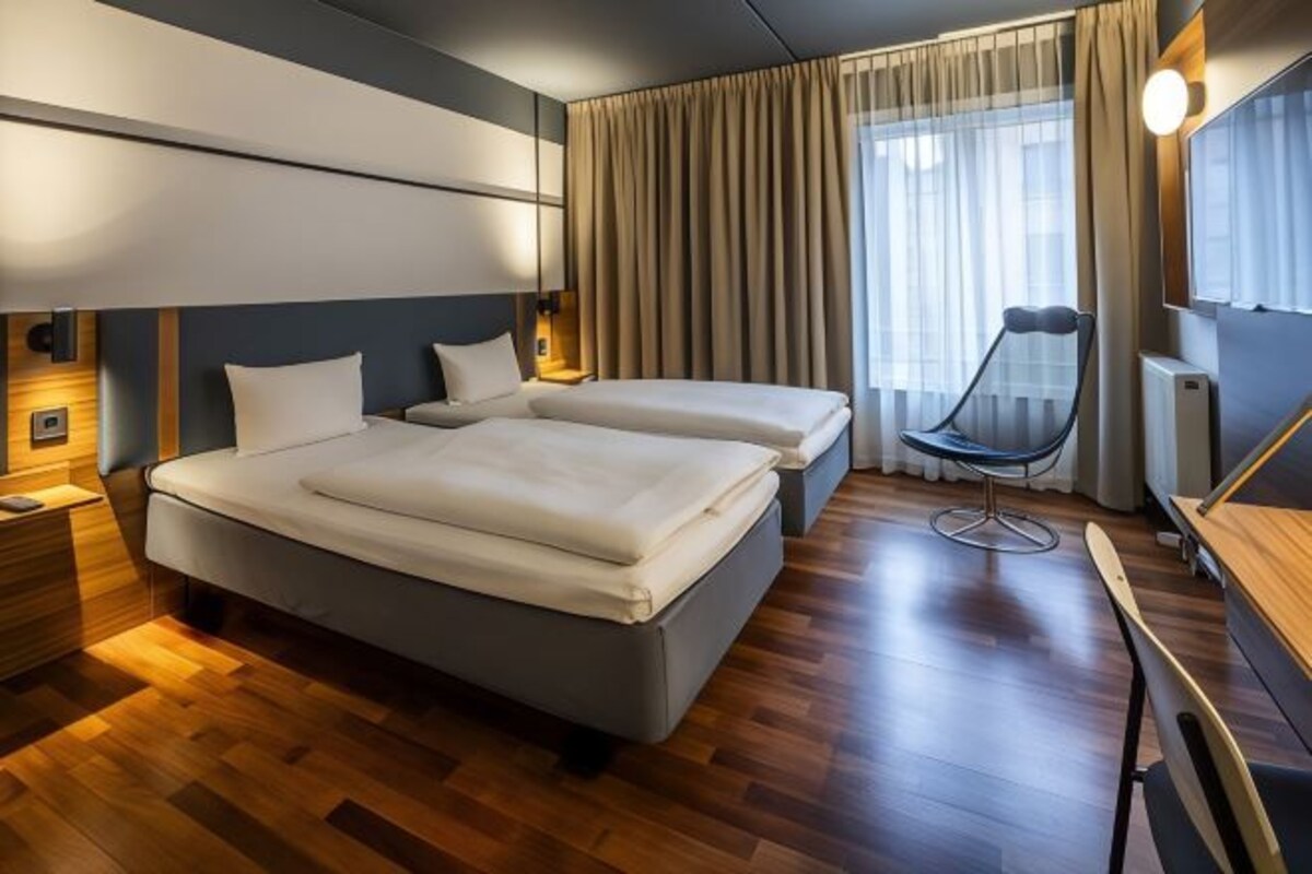 Une chambre d’hôtel moderne, dotée d’un grand lit, d’un bureau et d’une chaise.