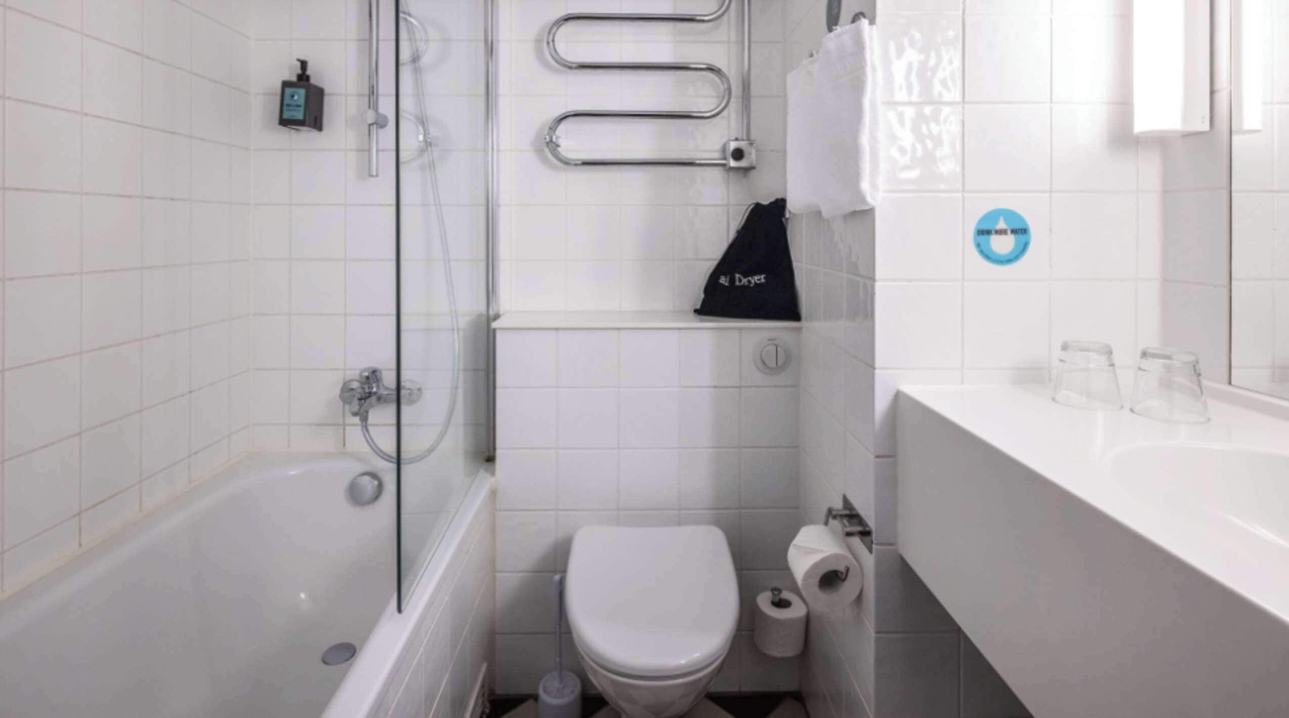 Een moderne badkamer met een douchecabine van glas, een wit toilet en een wastafel met een handdoekhouder.