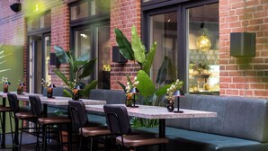 An outdoor dining area with brick walls, large windows, and green plants. - Comfort Hotel Vesterbro (Copenhagen)