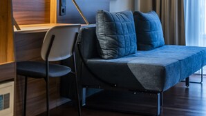 A modern room with a sofa, a chair, a flat-screen TV mounted on the wall, and a window with curtains. - Comfort Hotel Vesterbro (Copenhagen)