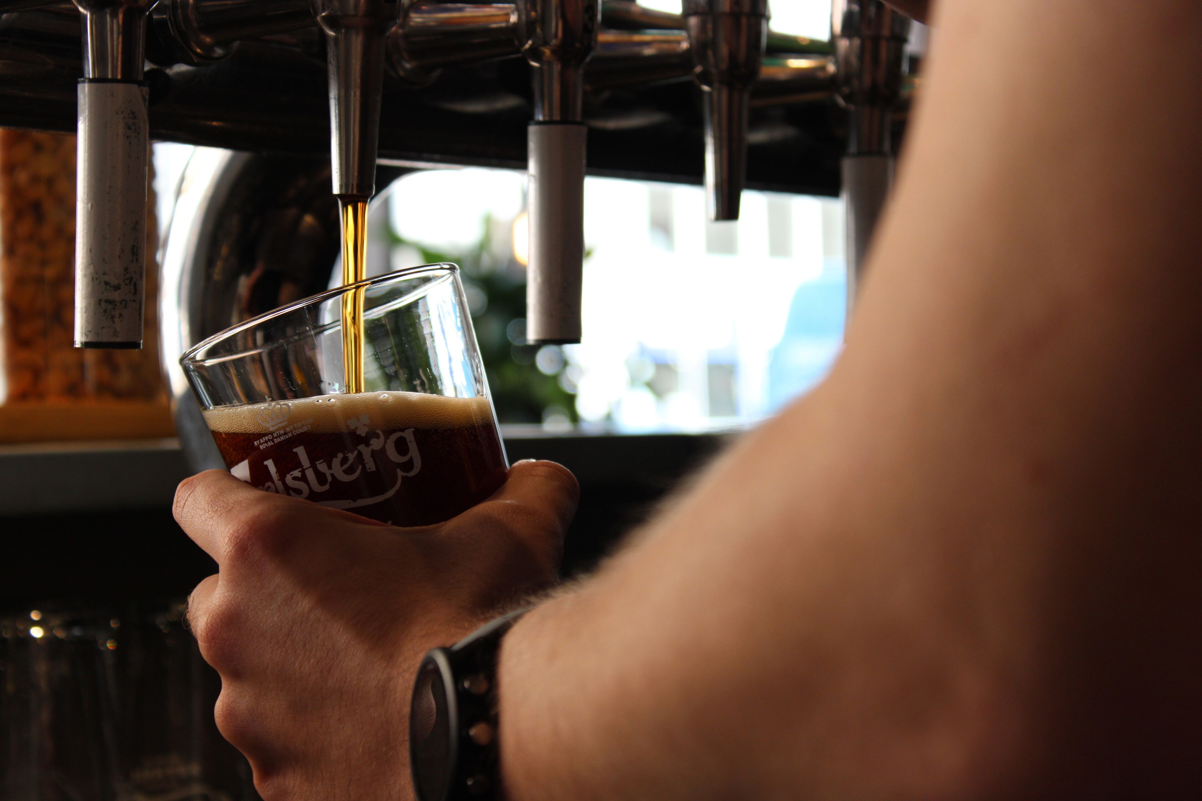 A person holding a glass with a beverage being poured into it.