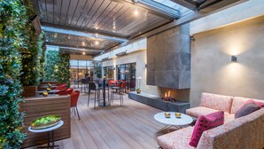 Un vaste espace intérieur doté d’un plancher en bois, de coins salon, d’une cheminée et d’un grand mur de verre.