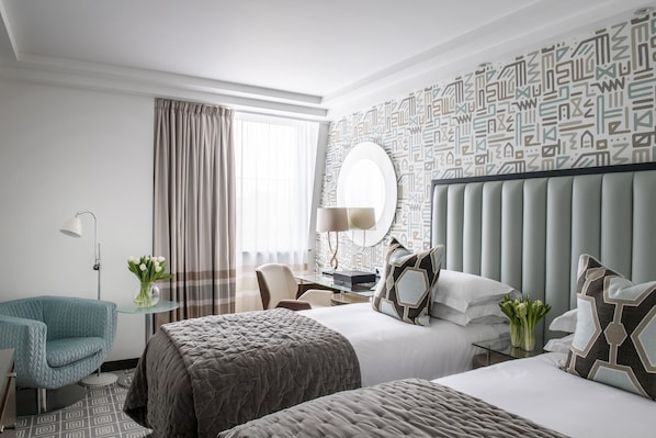 A hotel room with a large bed, a smaller bed, a desk with a chair, a sofa, and a large mirror. - The Marylebone Hotel (London)