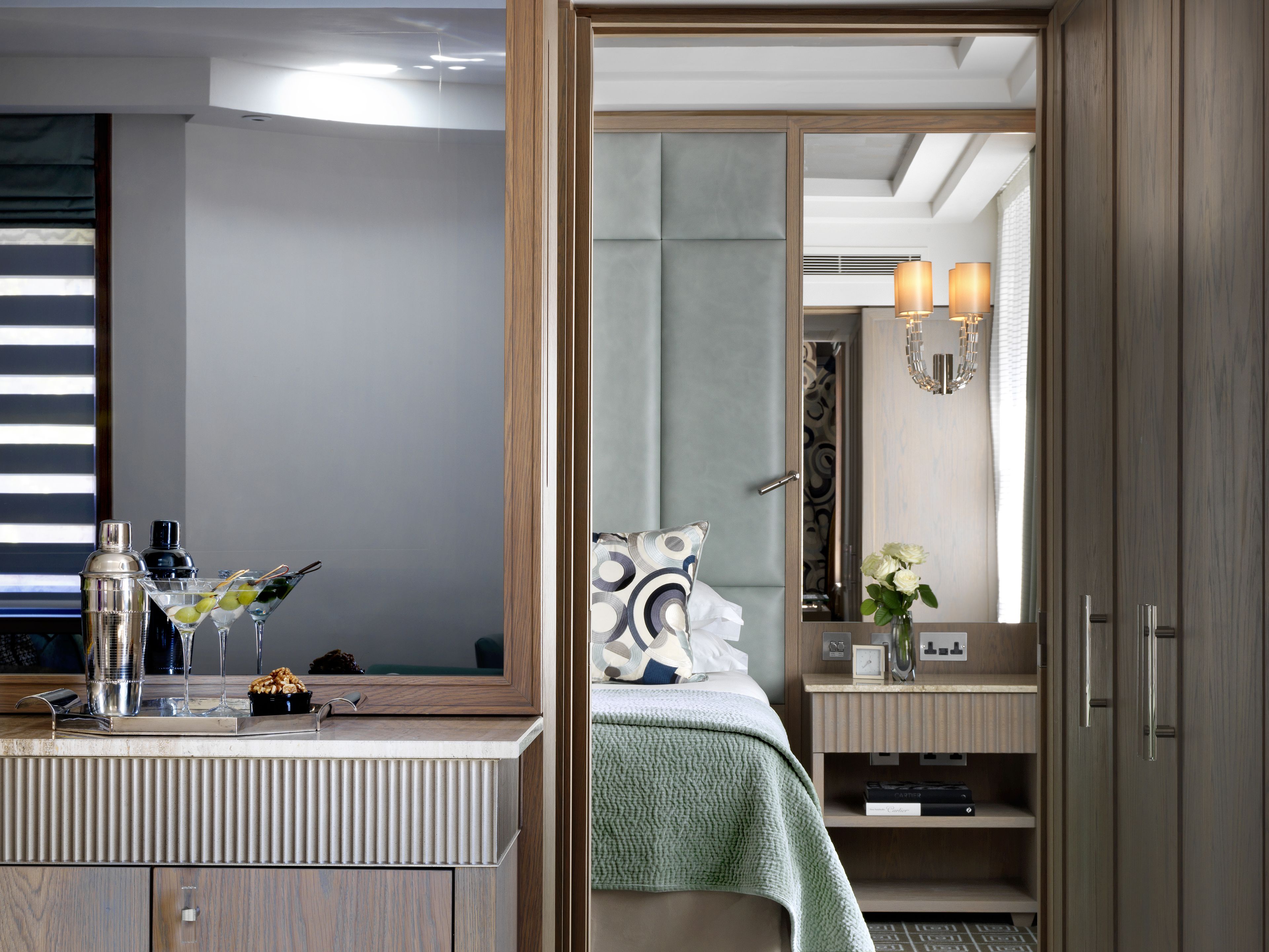 Ein modernes Hotelzimmer mit einem großen Spiegel, einem Nachttisch mit Lampe und einem ordentlich bezogenen Bett.