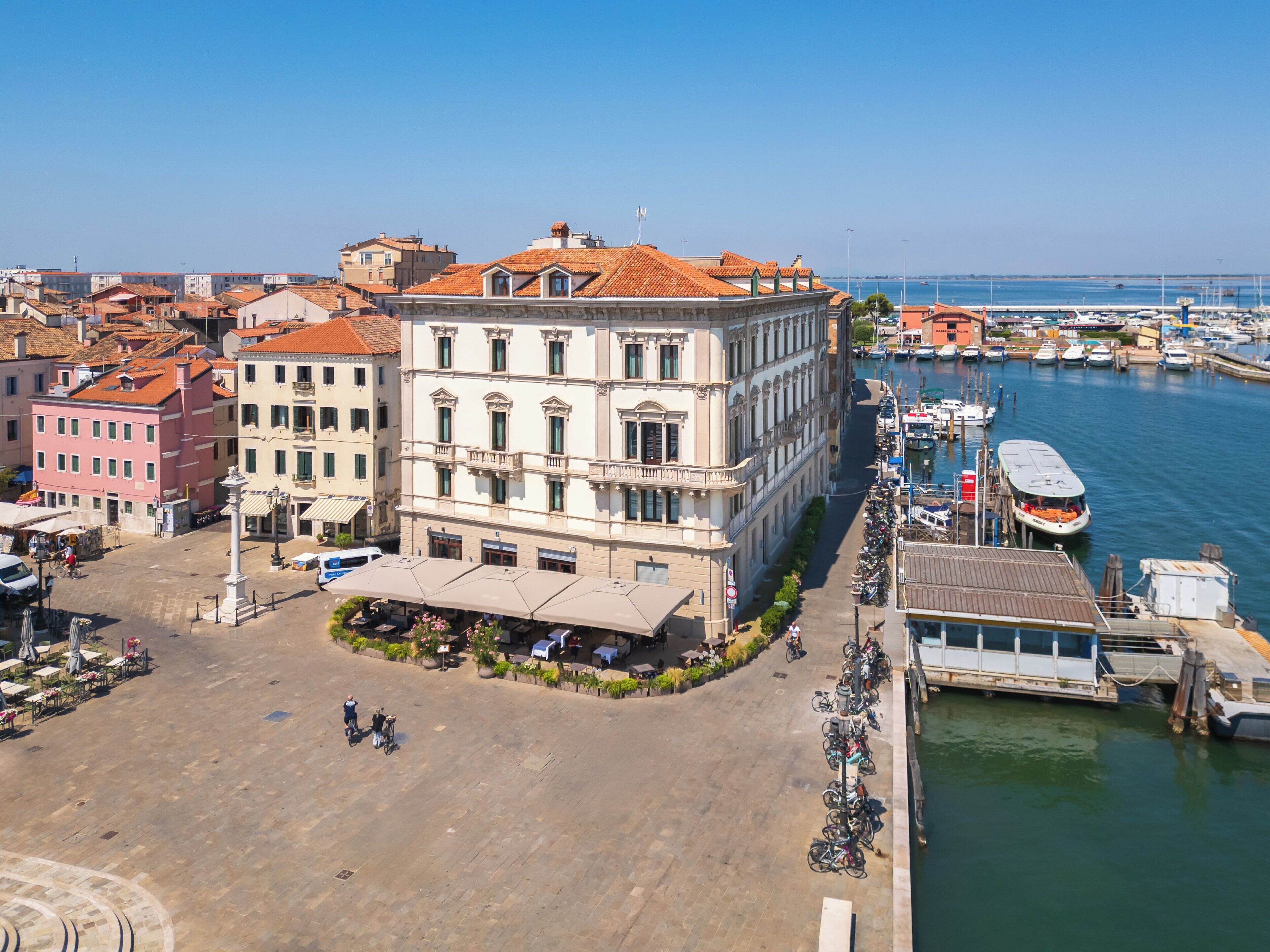 Ein Gebäude am Wasser mit einem zentralen Innenhof, umgeben von weiteren Gebäuden und einem Yachthafen.