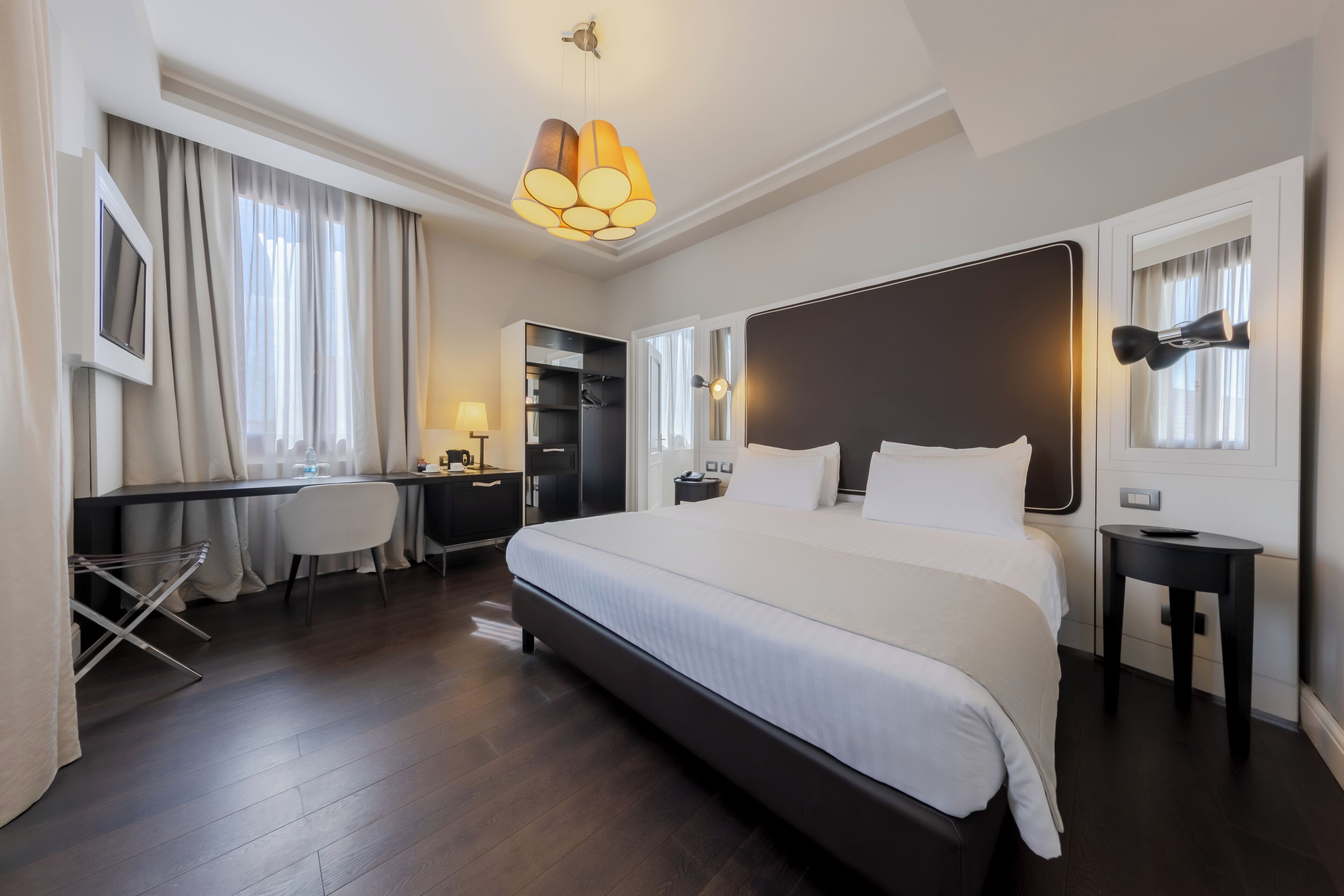 Quarto de hotel moderno com uma cama grande, uma escrivaninha e uma cadeira.