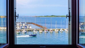 Ein Yachthafen mit mehreren vertäuten Booten, einer anlegenden Mole und freiem Blick auf das Wasser und das entfernte Ufer.