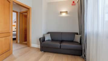 A modern living room with a dark leather sofa, wooden flooring, and a visible door leading to another room.