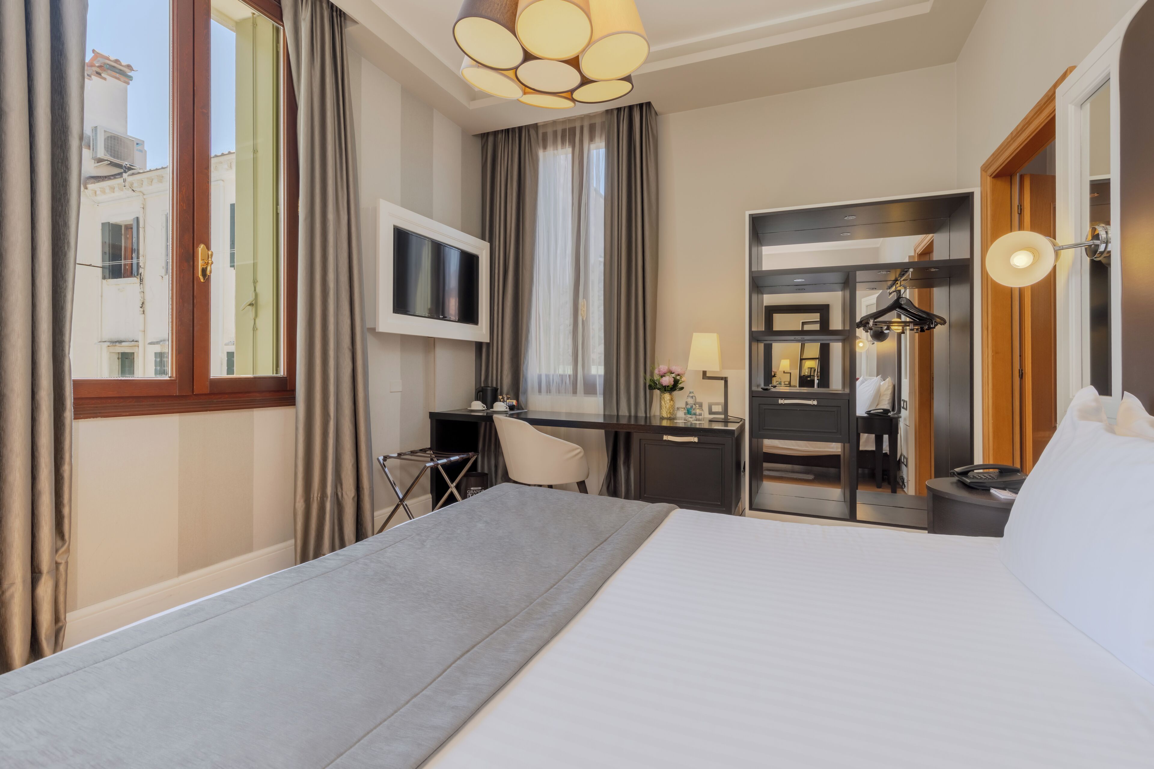 Ein Hotelzimmer mit Bett, Schreibtisch, Stuhl, Fernseher und Spiegel.